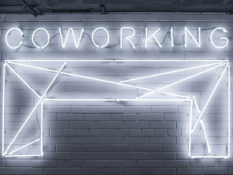 a neon sign for coworking on a brick wall